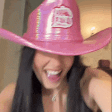 a woman is wearing a pink cowboy hat with the letter b on it .