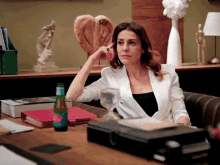 a woman sits at a desk with a bottle of acqua panna