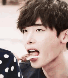 a young man is eating a piece of food with his tongue hanging out .