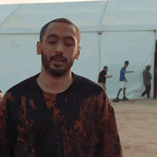 a man with a beard is standing in front of a tent in the desert .
