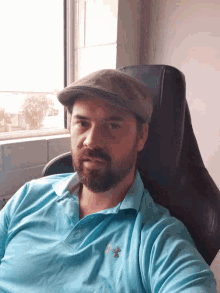 a man with a beard wearing a hat and a blue shirt