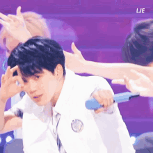 a man in a white shirt and tie is holding a blue microphone while dancing on a stage .