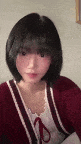 a girl with short black hair is wearing a red cardigan and a white top