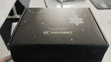 a person is holding a black box that says amusnet on it