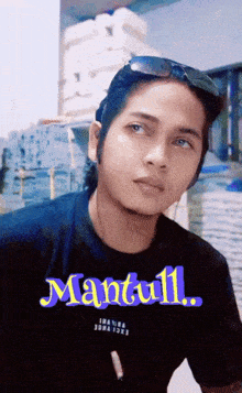 a man wearing sunglasses and a black shirt with the name mantull on it