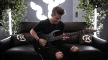 a man playing a guitar on a black couch