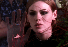 a close up of a woman 's face with a red string coming out of her hand