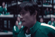 a man in a green jacket stands in front of a crowd