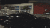 a black corvette is driving down a street at night .