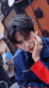 a young man wearing a blue jacket and red sleeves is making a face
