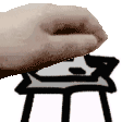 a close up of a person 's hand holding something over a table .
