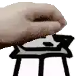 a close up of a person 's hand holding something over a table .