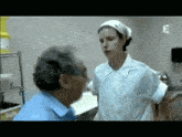 a woman in a nurse 's uniform talks to an older man