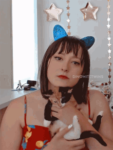 a woman holding a kitten with the name dinomitetwins on her chest