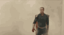 a man in a superhero costume is standing in the middle of a smokey area .