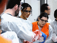 a group of people wearing safety goggles and gloves are standing in a room