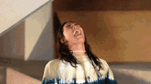 a man wearing a tie dye shirt is laughing with his mouth open