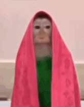 a monkey is wrapped in a pink towel and wearing a white mask .