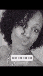 a woman with curly hair is wearing a necklace and says bjuuuuuu