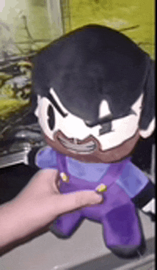 a person is holding a stuffed animal that looks like a cartoon character .