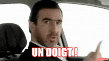 a man with a beard is sitting in the driver 's seat of a car and making a funny face .