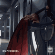 a woman in a red cape is standing next to a man in a suit .