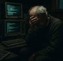 a man covering his face in front of a computer monitor that says ' a ' on it