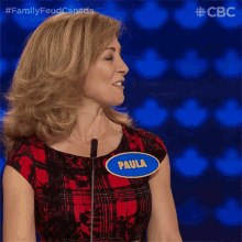a woman with a name tag that says paula stands in front of a microphone