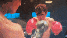 a man wearing red boxing gloves is fighting another man in a boxing ring