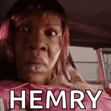 a woman with pink hair is sitting in a car with the words hemry written on her face .