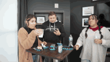 a man wearing a lonesome dog ranch sweatshirt stands next to two women