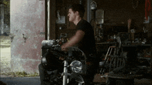 a man in a black shirt is standing next to a motorcycle in a garage