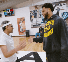 a man wearing a hoodie that says cuts glory shakes hands with another man