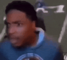 a man in a blue shirt is making a funny face while looking at the camera .