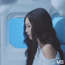 a woman with long black hair is sitting on an airplane with the letters ms on the bottom right