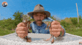 a man in a hat is holding two frogs in front of a sign that says k2 now