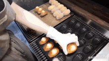 a person wearing white gloves is putting a donut in a pan with the words made in animatica on the bottom