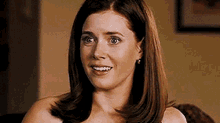 a woman is sitting on a couch smiling at the camera .