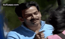 a man with a mustache is smiling and pointing at a woman in a pink shirt .