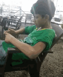 a young boy is sitting in a chair wearing a green shirt that says ' bangladesh ' on the front