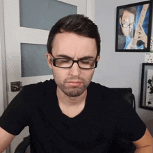 a man wearing glasses is sitting in front of a framed picture of a guitar player