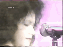 a close up of a woman singing into a microphone with rai written on the bottom