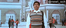 a man in a striped vest is walking in front of a building with the hashtag @newt_sch above him