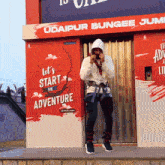 a man standing in front of an advertisement for udaipur bungee jumps