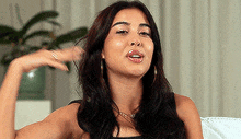 a woman with long dark hair is sitting on a couch and talking .