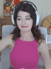 a woman in a pink top is wearing headphones and making a face