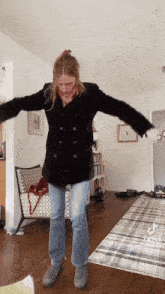 a woman in a black coat and jeans is dancing
