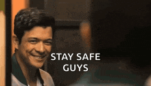 a man is smiling with the words `` stay safe guys '' written below him .