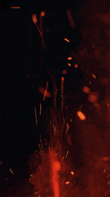 a fire with sparks coming out of it and a dark background