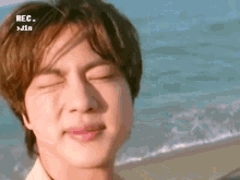 a close up of a person 's face while standing on a beach with their eyes closed .